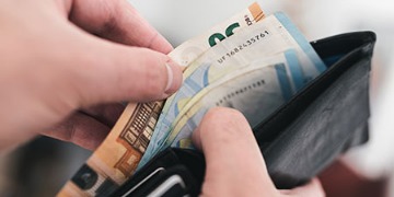 Hand greift in Geldbeutel mit einigen Euro-Scheinen