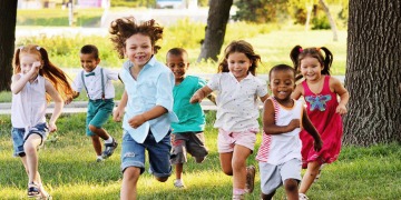 sieben Kinder die in einem Park auf einen zu rennen, im Hintergrund sind Bäume